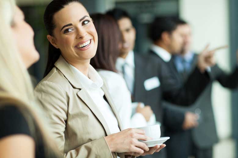 A woman smiles while holding a great tasting hot beverage.